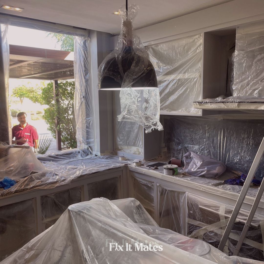 Fix It Mates team preparing a kitchen for cabinet painting by carefully packing and protecting appliances and surfaces to ensure a clean, professional finish